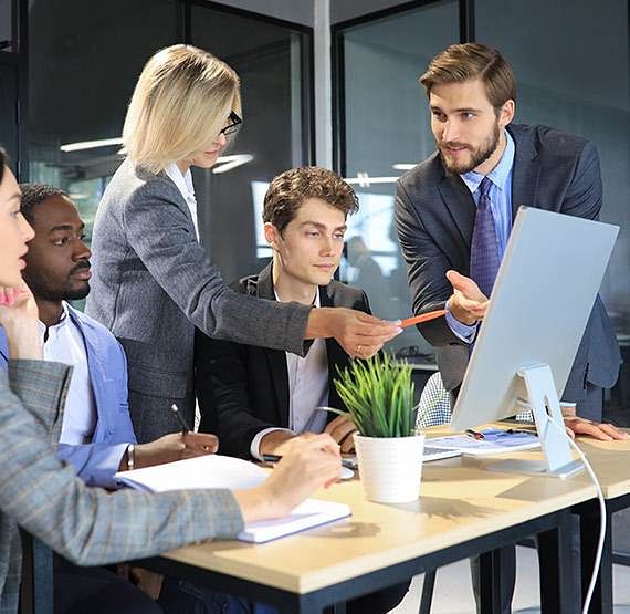 A group of people in organization discussing over a desktop screen